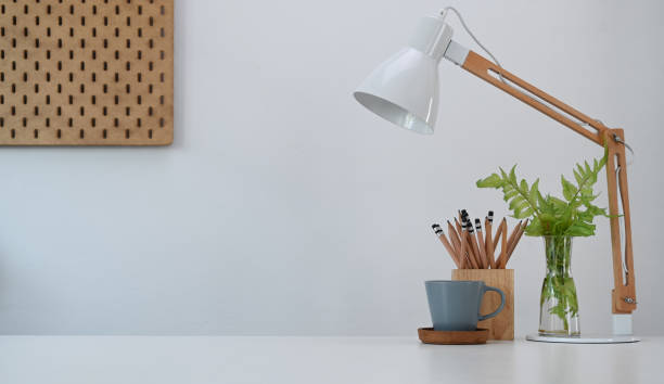 istock Simple workplace with lamp, pencils holder, coffee cup and plant on office desk. 1308366932
