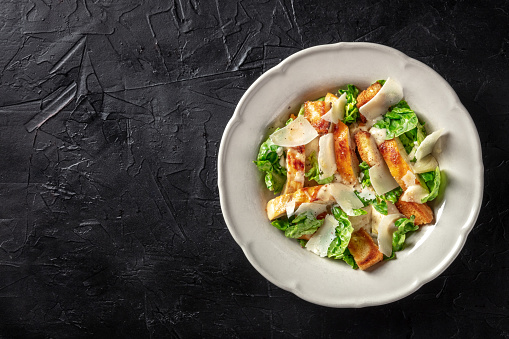Caesar salad with chicken, overhead shot with a place for text on a black background