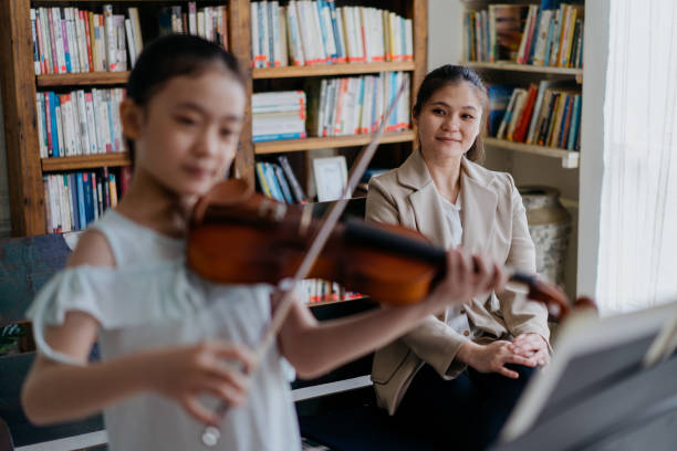 istock Young mother watching her daughter performing violin 1308368993