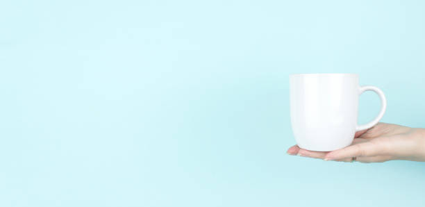 istock Close-Up Of Hand Holding White Cup Against Blue Background. 1308370058
