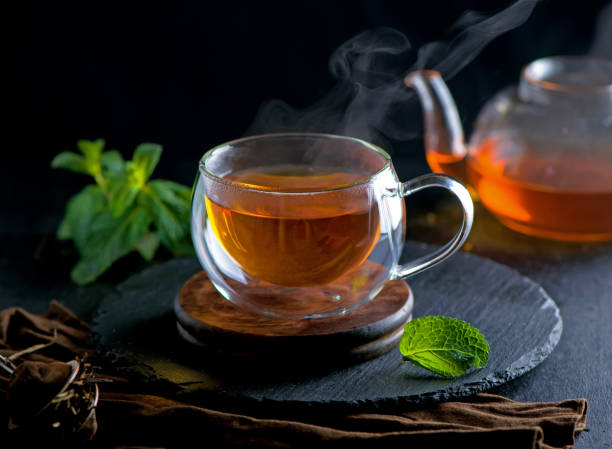 istock Tea concept, teapot with tea surrounded on wood background, tea ceremony, green tea in a transparent cup 1308370070