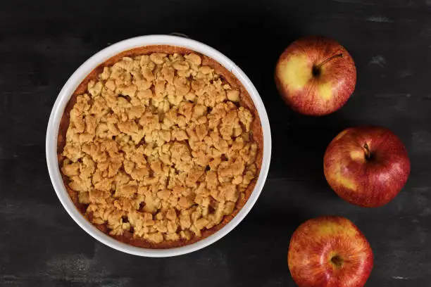 Photo of Top view of whole traditional European apple pie with topping crumbles in white springform pan