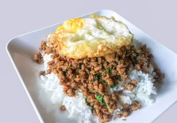 Fried basil leaves with pork and fried egg on rice Thai food grey background stock photo