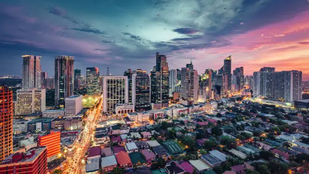 Makati Metro Manila Cityscape Panorama. Vibrant sunset over Makati in Downtown Manila. Aerial view along the urban main city streets from moving traffic. Illuminated urban city road under colorful moody skyscape. Downtown Makati, Manila, Philippines, Southeast Asia