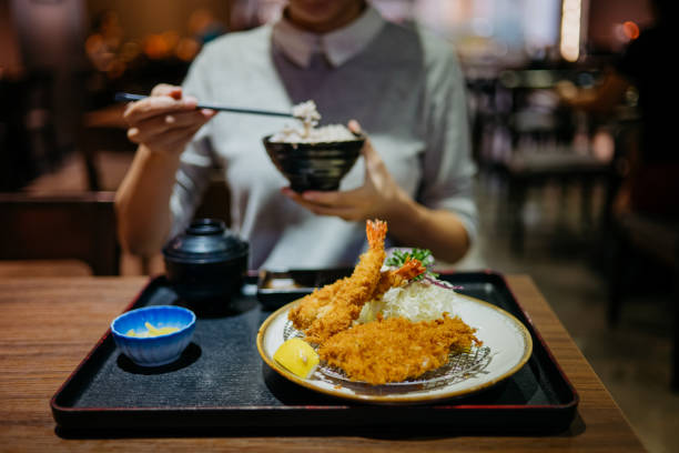 junge frau isst japanische tonkatsu mahlzeit in einem restaurant - tonkatsu stock-fotos und bilder