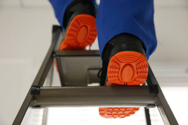 Professional worker climbing up ladder indoors, closeup. Low angle view