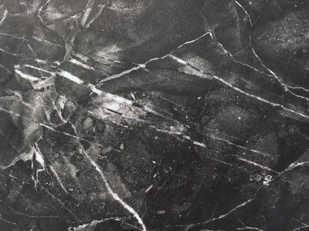 istock Texture of black marble with white lines of a pattern, macro background. Dark gray stone backdrop from mineral tile 1308377182