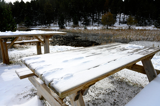 Snowed wooden table next to a mountain lake