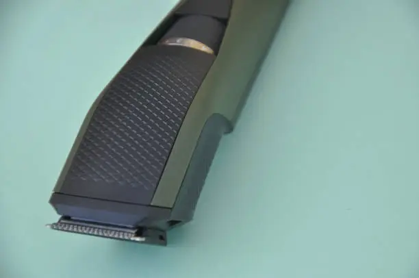 Close up shot of beard trimmer without comb isolated on green background.