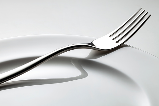 Fork on the plate on white background.