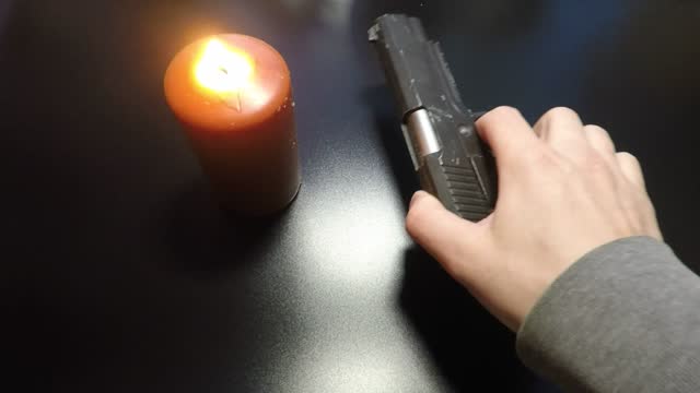 black background lighted candle and a gun