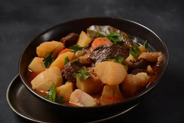 Photo of Irish stew made with beef, potatoes, carrots and herbs. Traditional St.Patrick's day dish, stewed in dark Guinness beer