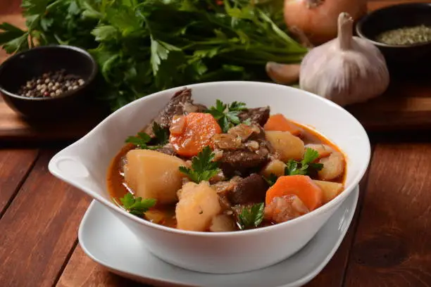 Photo of Irish stew made with beef, potatoes, carrots and herbs. Traditional St.Patrick's day dish, stewed in dark Guinness beer