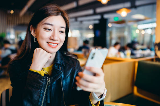 istock Asian young woman using mobile phone in restaurant. 1308384302