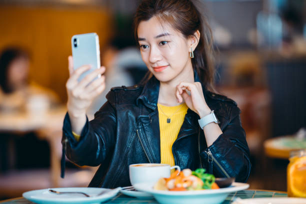 istock Asian young woman using mobile phone in restaurant. 1308384502