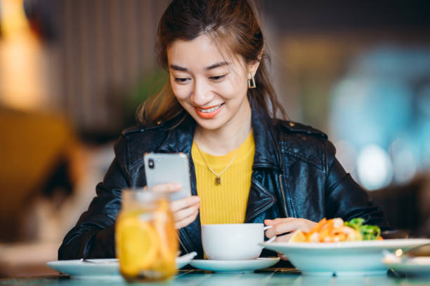 istock Asian young woman using mobile phone in restaurant. 1308384730