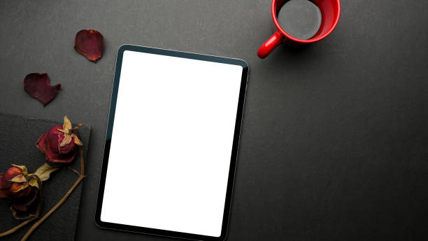 istock Top view of black table with digital tablet, notebook, dried roses, coffee mug and copy space 1308385700