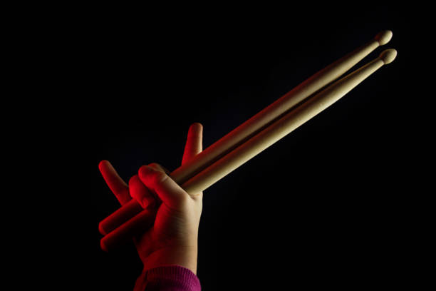 Child Hand Hold Wooden Drumsticks. Showing Devil Horns Sign Symbol Of Heavy Metal On Black Backlit Red Background. Rock Music Concept. Unrecognizable. Advertising Drum Lessons For Children. Soft Focus