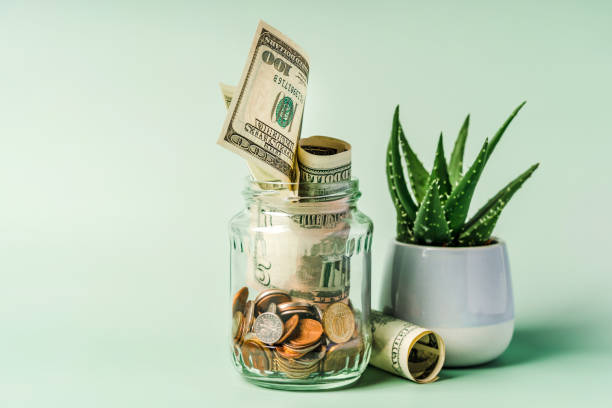 istock A glass jar with different coins on a pastel background with space for text. The concept of accumulating savings 1308388167