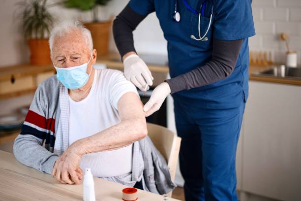 istock Senior man wearing face protective mask while receiving vaccine at home 1308388441