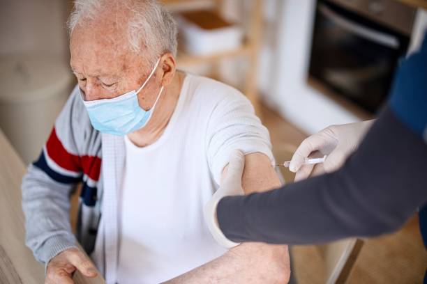 istock Senior man wearing face protective mask while receiving vaccine at home 1308388459