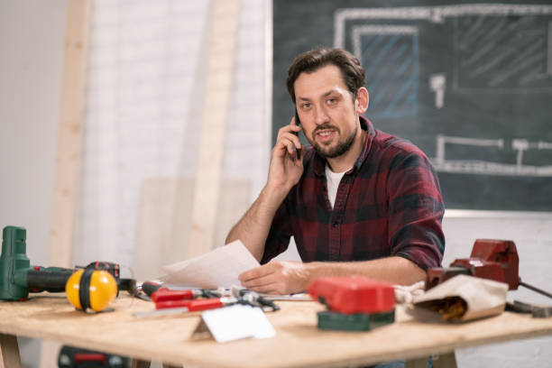 istock Smiling carpenter discussing projects with the client by phone 1308388472