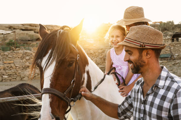 istock Happy family having fun riding on horse inside ranch 1308388615