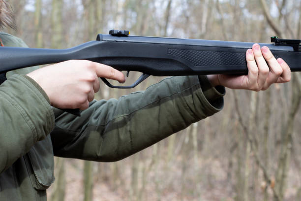 istock Young man shoot with air pneumatic rifle, spring daytime, hands holding gun 1308389781