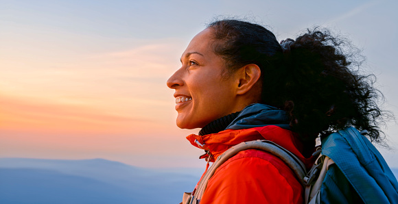 Side view of smiling mature woman looking at view while standing against sky.