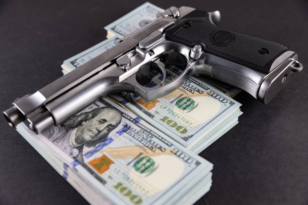 handfeuerwaffe auf dem us-dollar-stack - kriminelles geldkonzept - guns and money stock-fotos und bilder