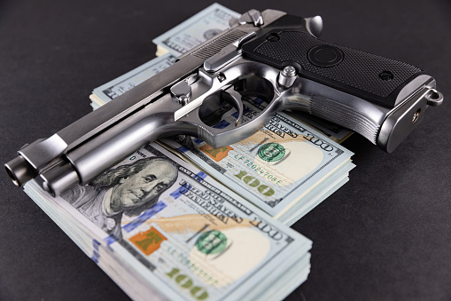 Handgun on the US dollars stack - - criminal money concept