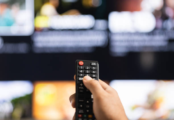 istock Close up male hand holding remote control pointing to change the programme television. 1308394489