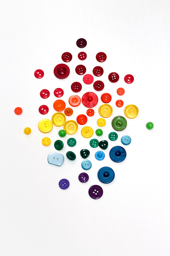 Group of plastic colorful buttons on white background. Rainbow colors red, orange, yellow, green and blue tailor texture.