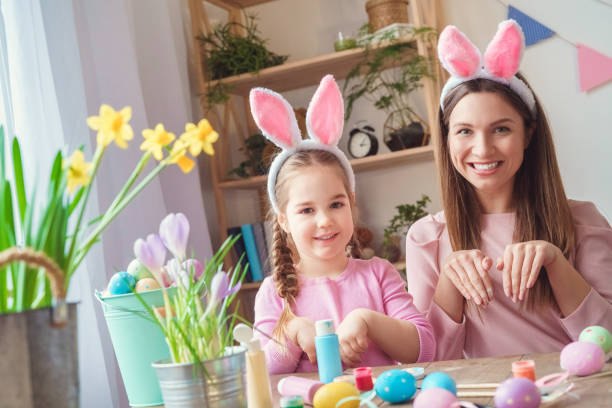 istock Mother and daughter together at home easter preparation in bunny ears rabbit pose 1308395078