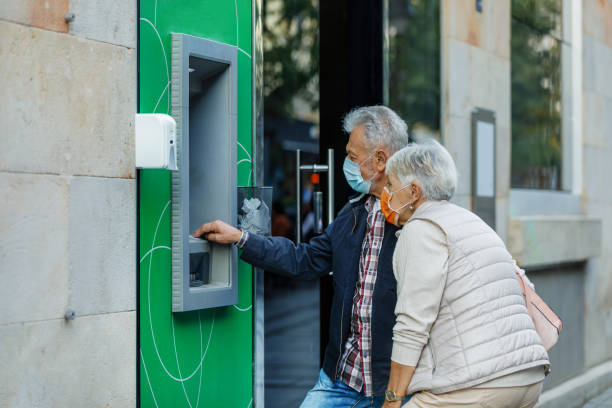 istock Senior Couple with Face Masks is Using an ATM Machine. 1308395265