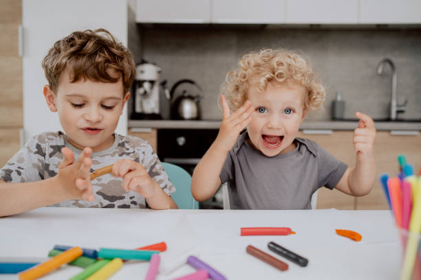 istock The happy siblings are sitting at the kitchen table playing with plasticine. A school-aged boy and a preschool-aged girl spend their free time together 1308396357