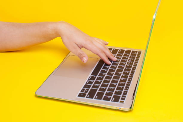 istock Hand on laptop keyboard on a yellow background. Concept work remotely. Freelance work 1308397985