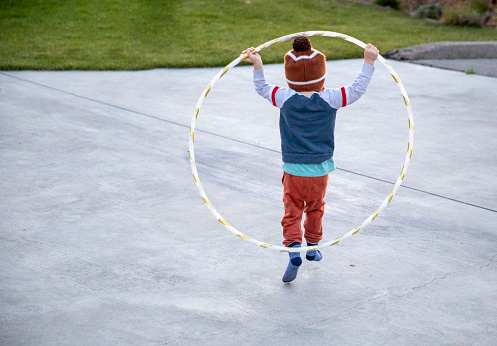 A little boy running with a hula hoop