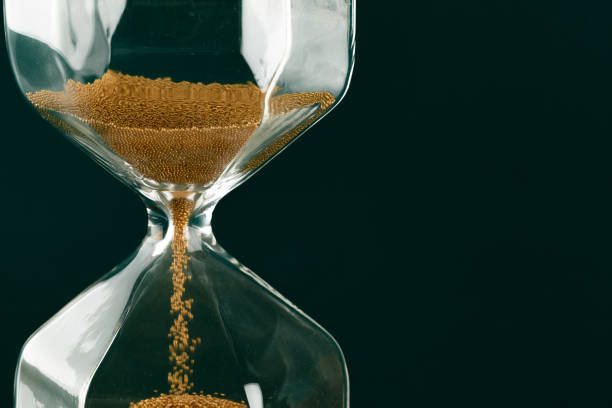 istock Gold hourglass on dark green paper background 1308398148