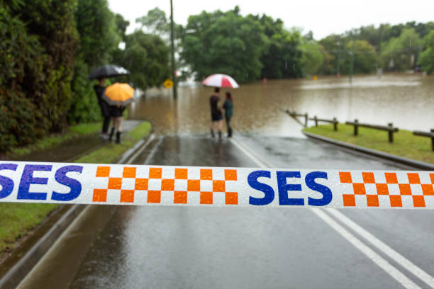 Windsor, Australia - March 22, 2021;  SES tape across a flooded road in Windsor Windsor, Australia - March 22, 2021; SES (State Emergency Services) tape stretched across a flooded road as locals look on.  Extreme weather caused flooding not seen in over 50 years. new south wales stock pictures, royalty-free photos & images