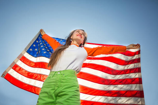 istock Woman with american flag over blue sky 1308400799