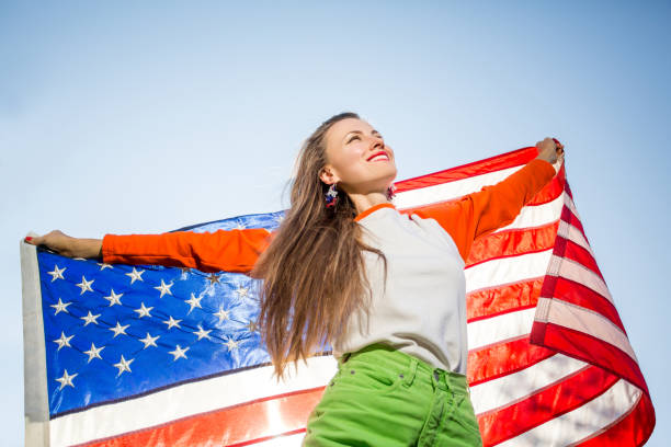 istock Woman with american flag over blue sky 1308400819