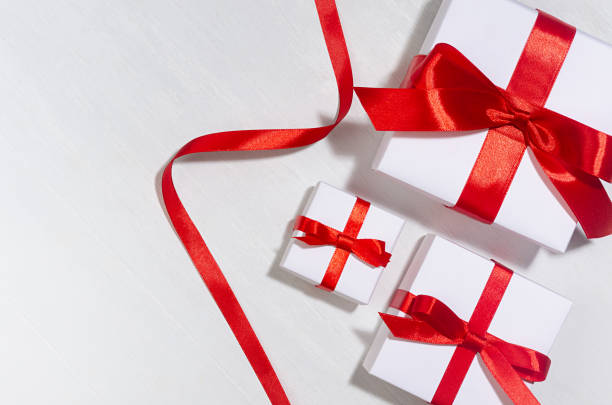 istock Gentle wedding set of white gift boxes with red bow on white wood board, copy space, top view. 1308402448