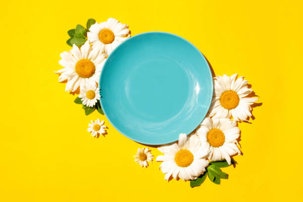 istock Blue empty plate and daisies on a yellow background. Contrast shadows 1308403763