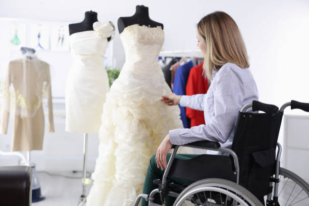 mulher em cadeira de rodas examina vestido de noiva em salão - wedding bride buying caucasian - fotografias e filmes do acervo