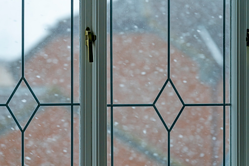 Looking out of a lounge window at snow falling during a snow shower in winter just after Christmas.