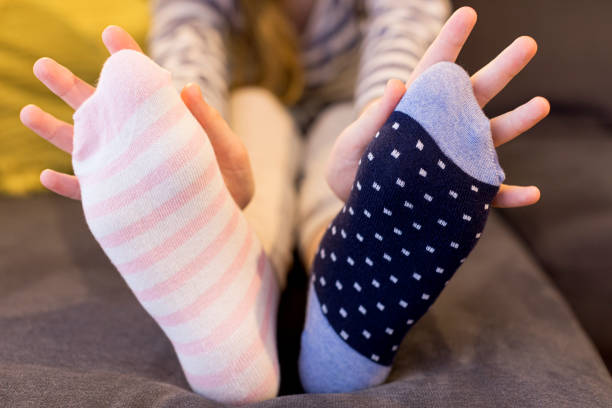 istock Down syndrome awareness concept. Girl wearing different socks while sitting on sofa at home. 1308410359