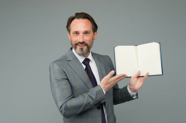 Take a look, read a book. Happy businessman show open book. Reading teacher in formal suit. School library. Literacy education. Literature lesson. Back to school. Read to succeed, copy space. echa un vistazo, lee un libro. feliz libro de negocios. profesor de lectura en traje formal. biblioteca de la escuela. educación para la alfabetización. lección de literatura. de vuelta a la escuela. leer para tener éxito, copiar espacio