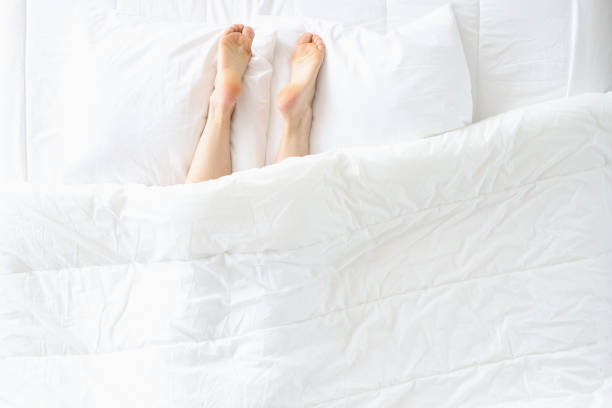 istock Women legs stick out from under blanket and lie on pillow 1308411955