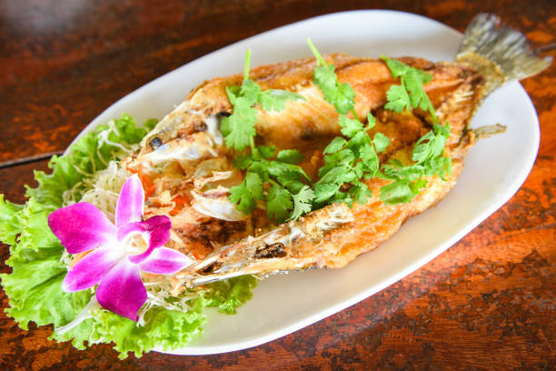 fried fish with herb and vegetable, cooked food sea bass fish fillet on plate on wooden table - sea bass prepared fish food grilled imagens e fotografias de stock